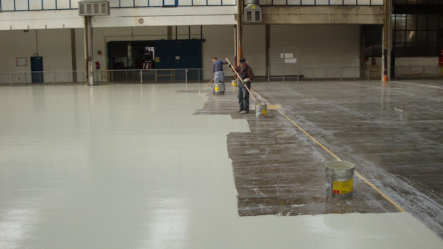 Zwei Personen bearbeiten einen Hallenboden